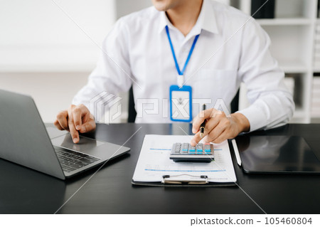 Men counting coins on calculator taking from the piggy bank. hand holding pen working on calculator to calculate on desk about cost at office. 105460804