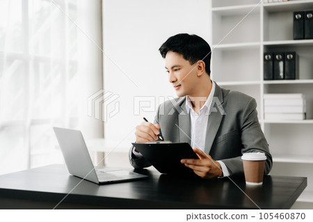Young business man working at office with laptop, tablet and taking notes on the paper.. 105460870
