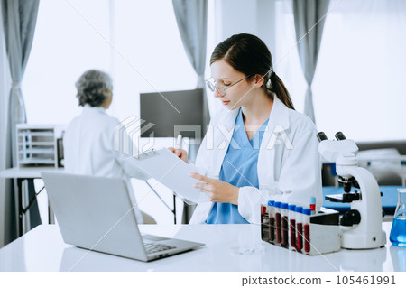 Two scientist or medical technician working, having a medical discuss meeting with an Asian senior female scientist supervisor in the laboratory with online reading, test samples and innovation Two scientist or medical technician working, having a medical discuss meeting with an Asian senior female scientist supervisor in the laboratory with online reading, test samples and innovation 105461991