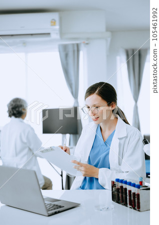 Two scientist or medical technician working, having a medical discuss meeting with an Asian senior female scientist supervisor in the laboratory with online reading, test samples and innovation Two scientist or medical technician working, having a medical discuss meeting with an Asian senior female scientist supervisor in the laboratory with online reading, test samples and innovation 105461992