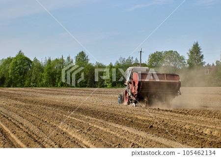 Potato planter is hitched to tractor during planting of potatoes during spring sowing period in plowed farmer field. Potato planter is hitched to tractor during planting of potatoes during spring sowing period in plowed farmer field. 105462134