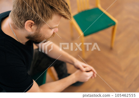 Close-up high-angle view of depressed young man crying during group psychotherapy session. Upset and anxious male sharing trauma story at therapy session. Concept of mental health, psychotherapy. Close-up high-angle view of depressed young man crying during group psychotherapy session. Upset and anxious male sharing trauma story at therapy session. Concept of mental health, psychotherapy. 105462555