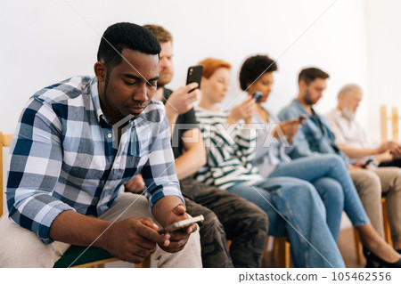 Selective focus of bored multicultural and different ages people in casual clothes sit on chairs in row waiting for job interview using typing mobile phones, recruitment hiring hr concept. 105462556