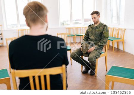 View from back of unrecognizable psychologist to young male soldier introducing and speaking about mental problems sitting in circle during PTSD group therapy session. Concept of mental health View from back of unrecognizable psychologist to young male soldier introducing and speaking about mental problems sitting in circle during PTSD group therapy session. Concept of mental health 105462596