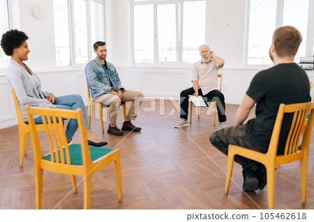 Remote portrait of professional male psychologist having conversation with multiethnic addicted people during therapy session, sitting in circle at modern doctors office. Concept of mental health. Remote portrait of professional male psychologist having conversation with multiethnic addicted people during therapy session, sitting in circle at modern doctors office. Concept of mental health. 105462618