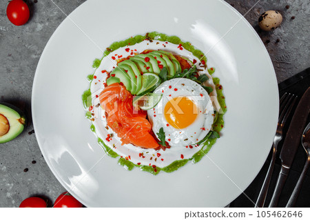 Poached eggs on top of smashed avocado on sourdough toast with smoked salmon. Healthy breakfast with plate on table. Top view. Copy space to right  105462646