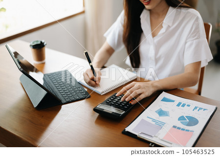 Women counting coins on calculator taking from the piggy bank. hand holding pen working on calculator to calculate on desk about cost at home office.. 105463525