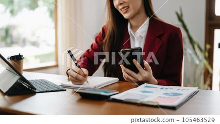 Women counting coins on calculator taking from the piggy bank. hand holding pen working on calculator to calculate on desk about cost at home office.. 105463529