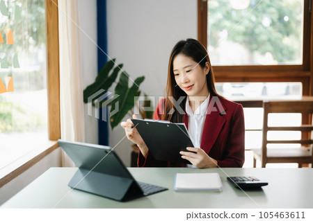 Beautiful Asian business woman typing laptop and tablet Placed at the table at the office.. Beautiful Asian business woman typing laptop and tablet Placed at the table at the office.. 105463611
