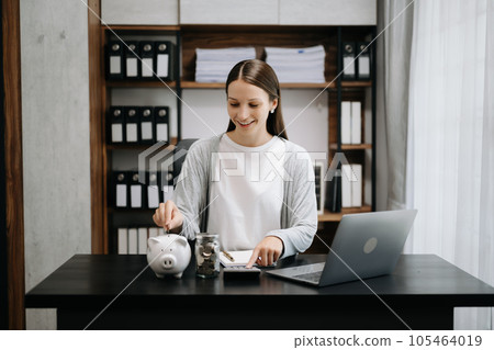 Caucasian Women are putting coins in a piggy bank for a business that grows for profit and saving money for the future. planning for retirement concept in office Caucasian Women are putting coins in a piggy bank for a business that grows for profit and saving money for the future. planning for retirement concept in office 105464019