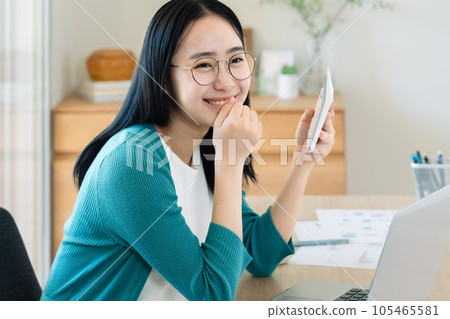 Young woman calculating with a computer and calculator Young woman calculating with a computer and calculator 105465581
