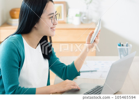 Young woman calculating with a computer and calculator Young woman calculating with a computer and calculator 105465594