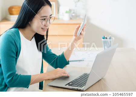 Young woman calculating with a computer and calculator Young woman calculating with a computer and calculator 105465597