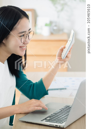 Young woman calculating with a computer and calculator 105465610