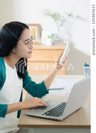 用計算機和計算器計算的年輕女子 用計算機和計算器計算的年輕女子 105465615