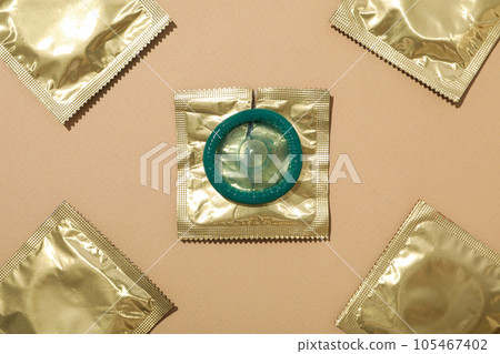 Condoms in a golden wrapper on a light background close-up Condoms in a golden wrapper on a light background close-up 105467402