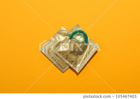 Green condoms on a yellow background close-up Green condoms on a yellow background close-up 105467403