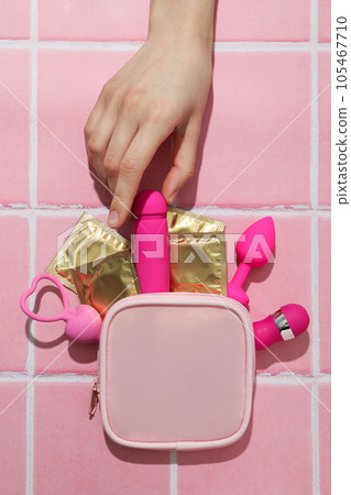Pink handbag with condoms and sex toys on a pink background 105467710