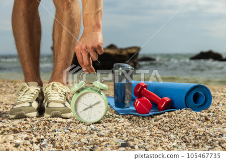 A watch, sneakers on a person, sports accessories on the beach A watch, sneakers on a person, sports accessories on the beach 105467735