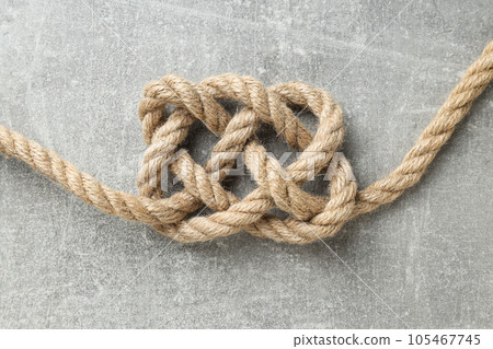 Thick knotted rope close-up on gray background 105467745