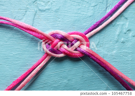 Braided cords tied together in the shape of an infinity sign on a blue background. Communication concept. Braided cords tied together in the shape of an infinity sign on a blue background. Communication concept. 105467758