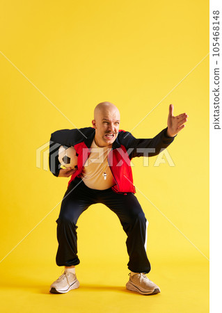 Image of balded and mustache young trainer with soccer ball over yellow studio background. Image of balded and mustache young trainer with soccer ball over yellow studio background. 105468148