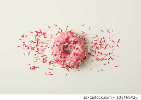 Donut with pink glaze and sprinkles on white background, top view 105469426