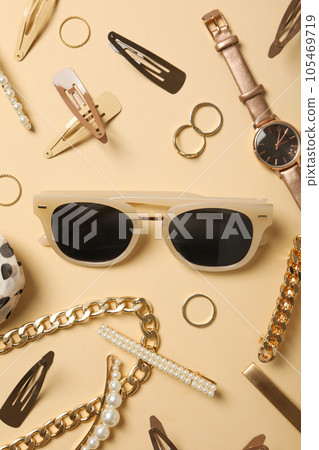 Beige sunglasses with feminine decorations around, on a beige background 105469719