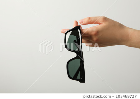 Sunglasses in hand with space for text, on light background 105469727