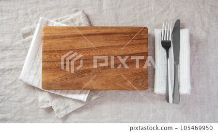 Wood plate with fork and knife on napkin on linen tablecloth, top view Wood plate with fork and knife on napkin on linen tablecloth, top view 105469950