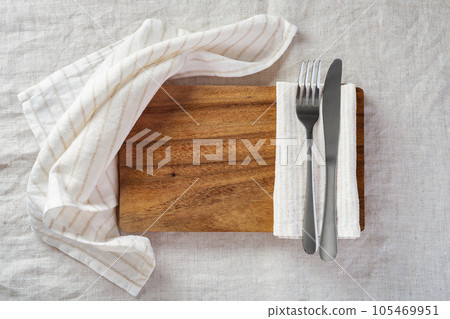 Wood plate with fork, knife and napkin on linen tablecloth, top view Wood plate with fork, knife and napkin on linen tablecloth, top view 105469951