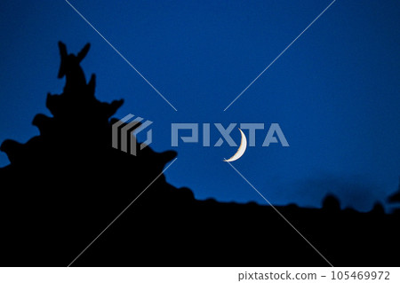 The crescent moon seen through the tiled roof The crescent moon seen through the tiled roof 105469972