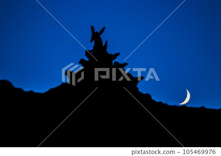 The crescent moon seen through the tiled roof The crescent moon seen through the tiled roof 105469976