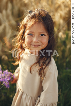 Child in a summer field. Little girl in a cute brown dress. Child in a summer field. Little girl in a cute brown dress. 105470010