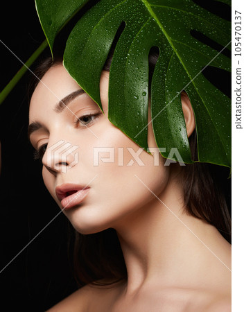 Beauty Portrait of brunette girl in palm leaves. Beautiful young woman with Make-up Beauty Portrait of brunette girl in palm leaves. Beautiful young woman with Make-up 105470137