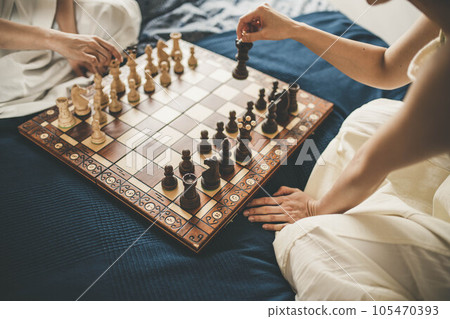 Two women playing chess in bed 105470393