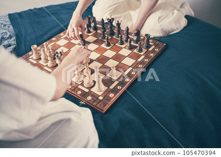 Two women playing chess in bed 105470394
