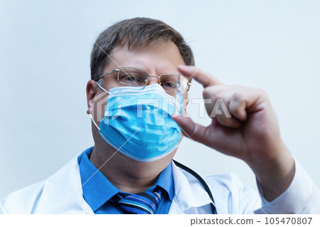 Male doctor looks at an ampoule with medicine vaccine, close-up white background 105470807