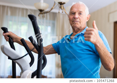Senior man with elliptical trainer at home Senior man with elliptical trainer at home 105471268