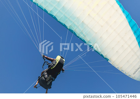 Paraglider in the sky. The sportsman flying on a paraglider. Paraglider in the sky. The sportsman flying on a paraglider. 105471446