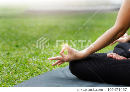 Asian woman practicing yoga in Root Bond, Mula Bandha pose on the mat in outdoor park. 105471467