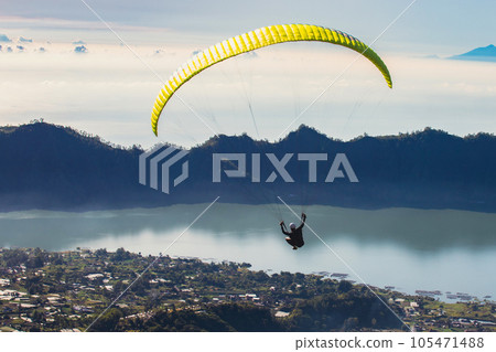 Paraglider flies in front of the lake Paraglider flies in front of the lake 105471488
