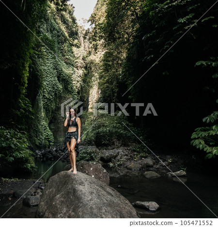 Woman stands on a stone in the jungle Woman stands on a stone in the jungle 105471552
