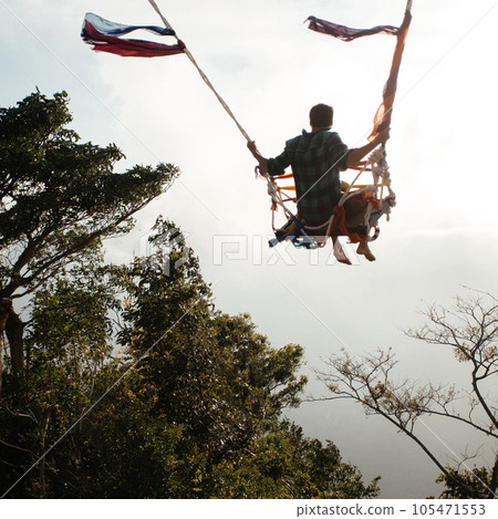 Man swinging on swing at the end of the world. 105471553