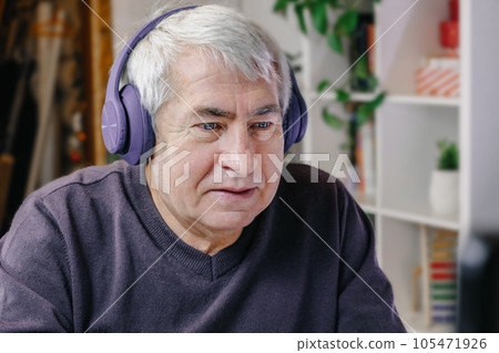 Happy senior man making video call at laptop. Old Man with headphones connected with laptop at home. Technology, people, lifestyle and communication Happy senior man making video call at laptop. Old Man with headphones connected with laptop at home. Technology, people, lifestyle and communication 105471926