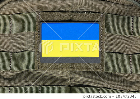 Patch on an adhesive tape with the Ukrainian flag on a military uniform, backpack, bag. Ukrainian flag attached to clothes or a bag with velcro. 105472345
