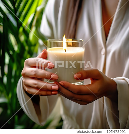Young woman holding burning candle jar in her hands, container candle mockup closeup shot, mindfulness home interior with green plants Young woman holding burning candle jar in her hands, container candle mockup closeup shot, mindfulness home interior with green plants 105472991