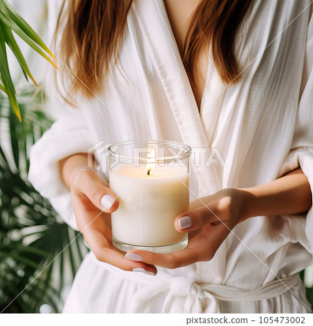 Young woman holding burning candle jar in her hands, container candle mockup closeup shot, mindfulness home interior with green plants Young woman holding burning candle jar in her hands, container candle mockup closeup shot, mindfulness home interior with green plants 105473002