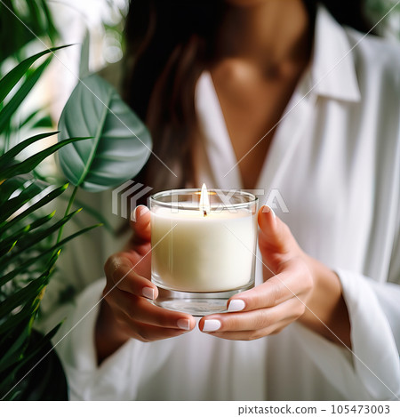 Young woman holding burning candle jar in her hands, container candle mockup closeup shot, mindfulness home interior with green plants Young woman holding burning candle jar in her hands, container candle mockup closeup shot, mindfulness home interior with green plants 105473003