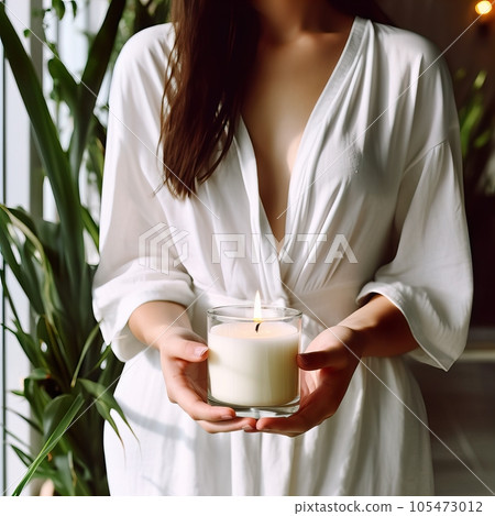 Young woman holding burning candle jar in her hands, container candle mockup closeup shot, mindfulness home interior with green plants Young woman holding burning candle jar in her hands, container candle mockup closeup shot, mindfulness home interior with green plants 105473012